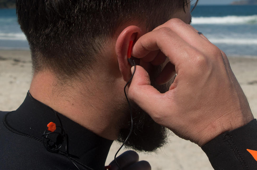 Picture showing a surfer putting earplug into the ear