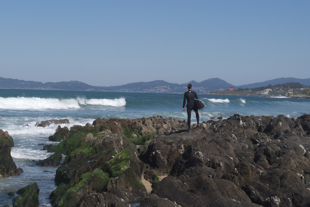 Zdjęcie surfera stojącego na skałach na plaży w Patos