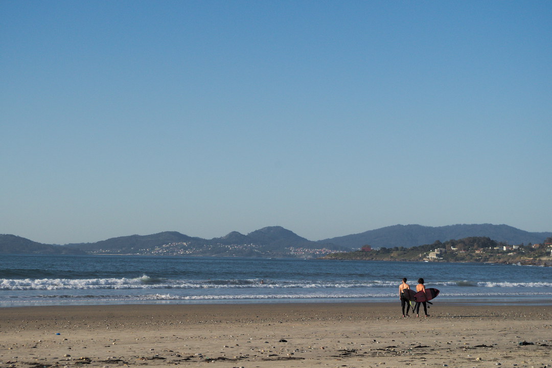 Picture of two surfers walking on Patos beach in Galicia