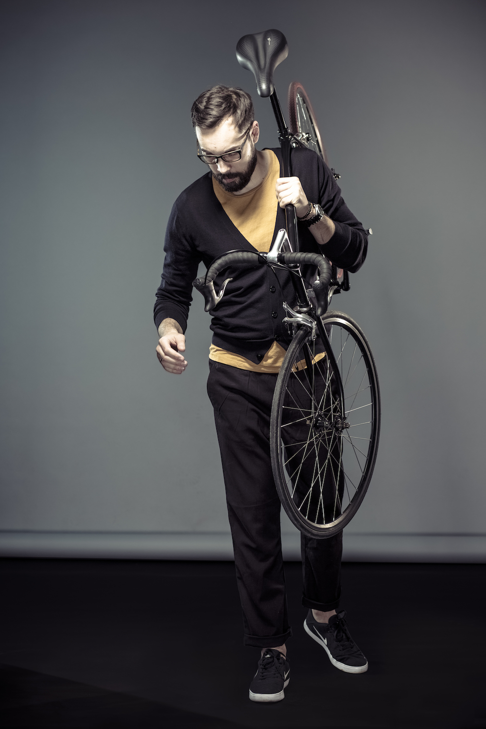 man wearing stylish cardigan and carrying a city bike