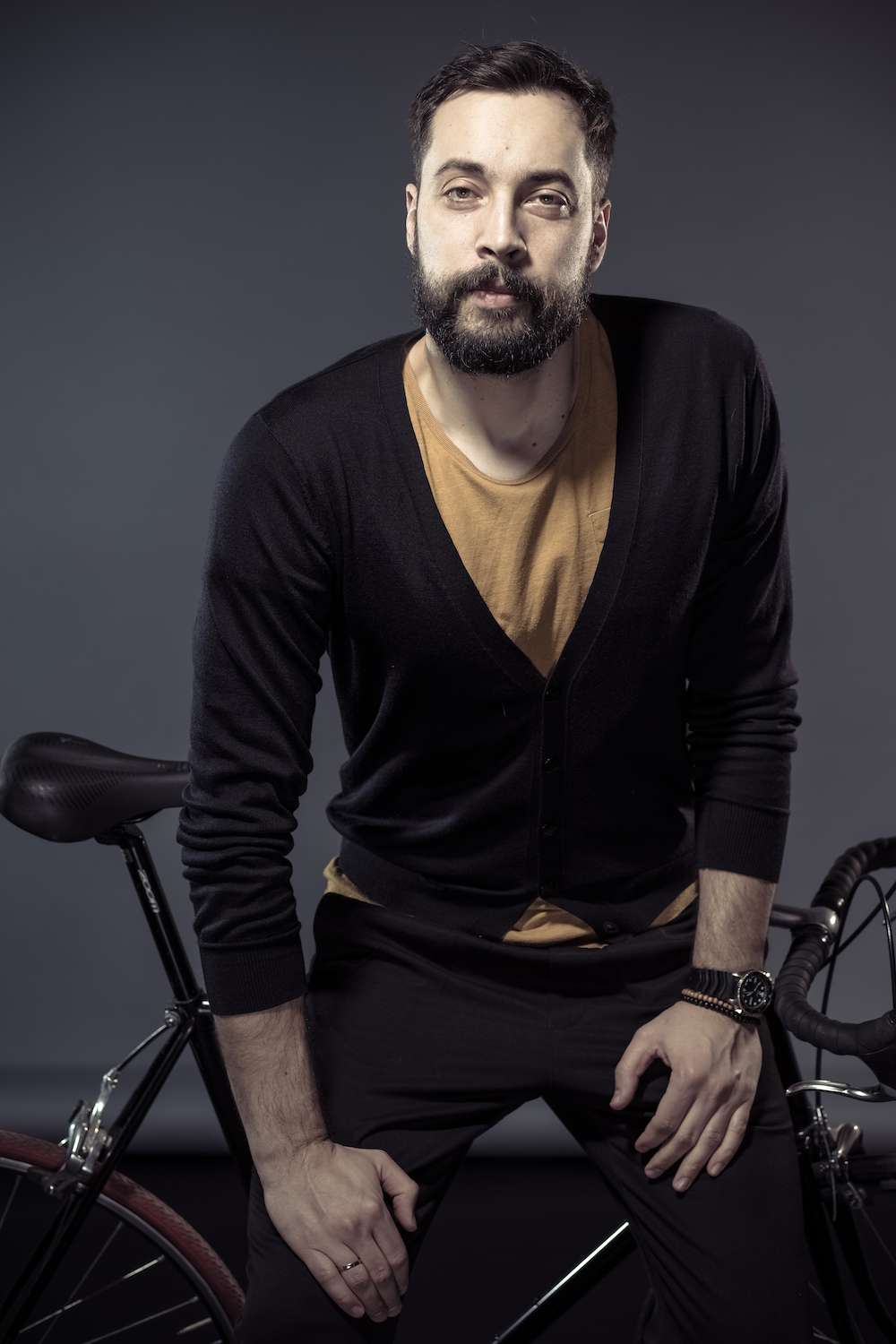 man wearing a black cardigan sitting on a bike