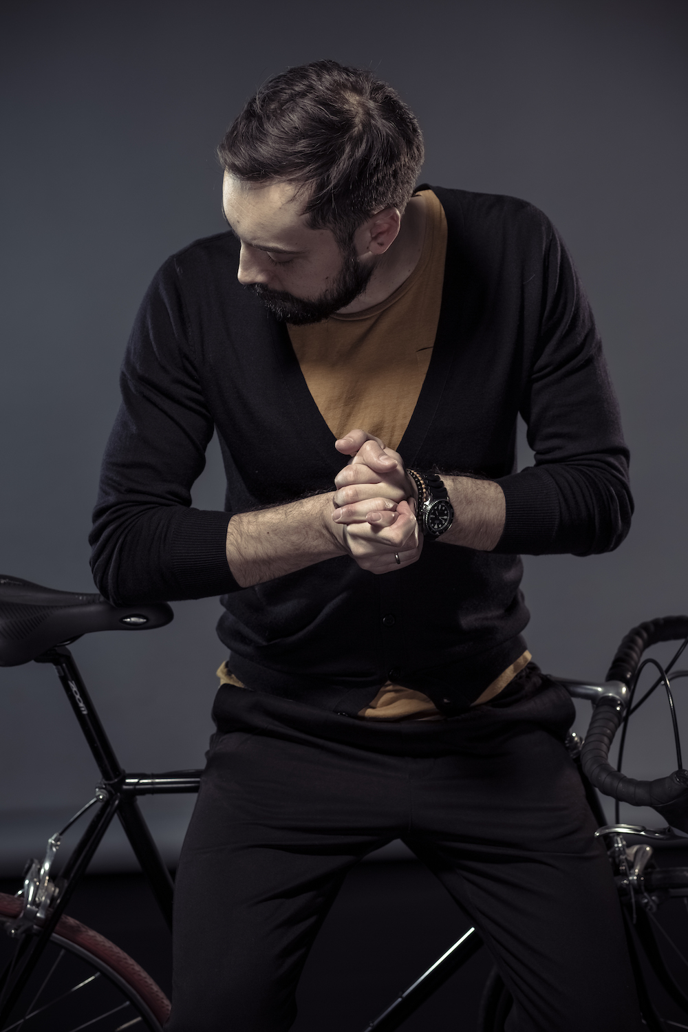man wearing a black cardigan sitting on a bike