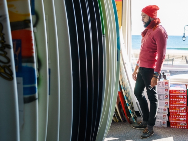 Image of surfer watching at surfboards in surf shop
