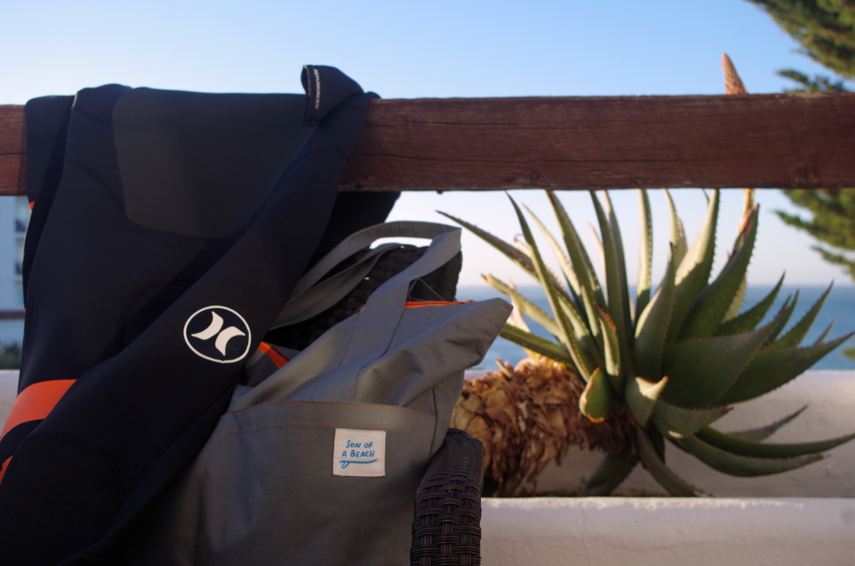 Hurley wetsuit and Son of a Beach tote bag on a balcony near a beach